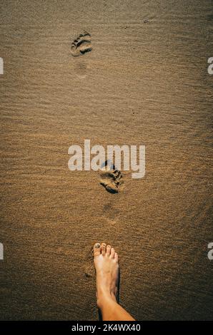 Frauenfuß am Strand, Sand mit Fußabdrücken Stockfoto