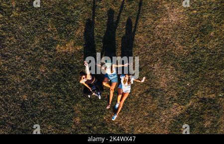 Vogelperspektive auf drei Frauen, die auf dem Gras liegen Stockfoto