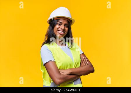 Positive junge Dame kreuzte die Arme, strahlendes Lächeln tragen Schutzausrüstung isoliert gelben Hintergrund Stockfoto