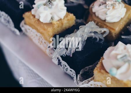 Kleine Scheiben cremiger köstlicher purpurner Yam AKA UBE Cake mit Macapuno-Belag AKA Coconut Sport und Zitronenpudding-Kuchen auf weißem Leinentisch. Stockfoto