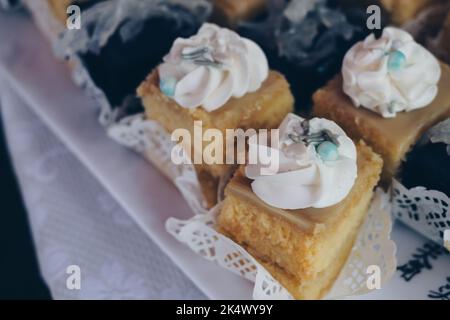 Kleine Scheiben cremiger köstlicher purpurner Yam AKA UBE Cake mit Macapuno-Belag AKA Coconut Sport und Zitronenpudding-Kuchen auf weißem Leinentisch. Stockfoto