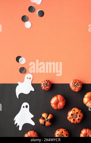 Niedliche Halloween vertikalen Hintergrund, Vorlage für Social-Media-Geschichten. Schwarz und orange flache Laie mit bemalten Deko-Kürbissen. White Paper Ghosts Stockfoto