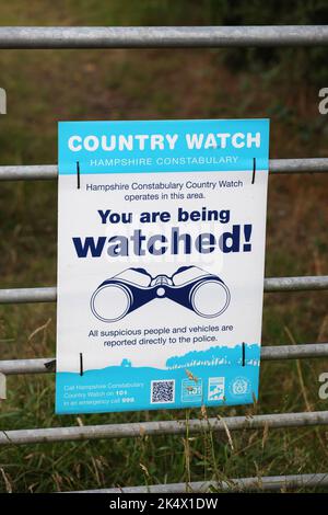 Ein Country Watch-Schild „You Are Being Watched“ an einem Farmtor in Hampshire, Großbritannien. Stockfoto