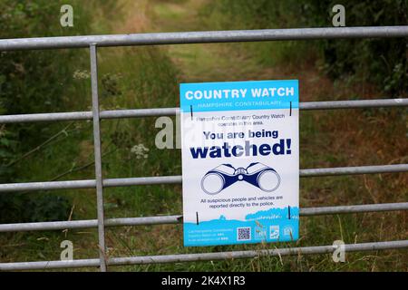 Ein Country Watch-Schild „You Are Being Watched“ an einem Farmtor in Hampshire, Großbritannien. Stockfoto