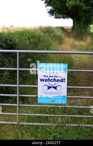 Ein Country Watch-Schild „You Are Being Watched“ an einem Farmtor in Hampshire, Großbritannien. Stockfoto