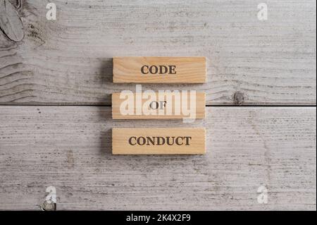 Code of Conduct Zeichen geschrieben auf einem Stapel von drei Holzblöcken über weiß strukturierten Holzhintergrund platziert. Stockfoto