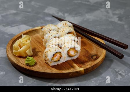 Satz Rollen auf einem runden Holzbrett auf grauem Hintergrund Stockfoto