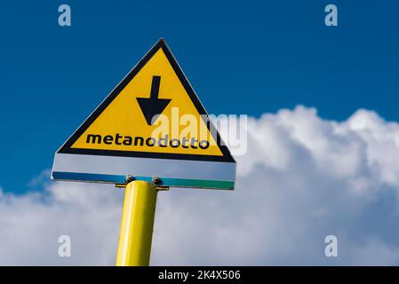 Schild, das das Vorhandensein von unterirdischer Methanleitung in Italien anzeigt, Metanodotto (Gaspipeline) Zeichen auf blauem Himmel und Wolke Stockfoto