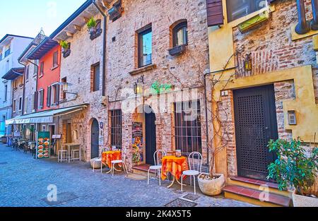 SIRMIONE, ITALIEN - 10. APRIL 2022: Die Reihe der historischen Häuser in der Via Casello mit kleinen Bars und Cafés, am 10. April in Sirmione Stockfoto