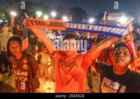 Kendari, Indonesien. 04. Oktober 2022. Ein Unterstützer von Persija Jakarta, der die Rivalen von Arema sind, stellt Shal Arema und Persija als eine Form der Wertschätzung während der Gebetsandacht an die Opfer des Kanjuruhan-Stadions dar. Die Kendari City Football Supporting Community hielt ein Gebet für die Anhänger des Malang Arema Clubs ab, die bei der Tragödie im Kanjuruhan Stadium, Malang, ums Leben kamen. (Foto von Andry Denisah/SOPA Images/Sipa USA) Quelle: SIPA USA/Alamy Live News Stockfoto