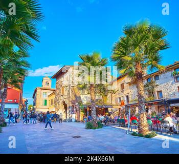 Die Reihe kleiner Restaurants unter den hohen Palmen, Piazza Flaminia, Sirmione, Italien Stockfoto