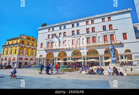 BRESCIA, ITALIEN - 10. APRIL 2022: Die überfüllte Piazza della Vittoria mit moderner Statue in Fontana del Bigio und Palazzo Assicurazioni Stockfoto