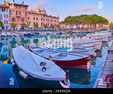 Genießen Sie den Sonnenuntergang in Porto Vecchio (Alter Hafen) mit Blick auf kleine Fischerboote, üppige Pinien und bunte Häuser, Desenzano del Garda, Lake Gard Stockfoto