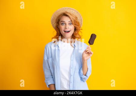 Sommerkonzept. Froh positive Frau hält leckere gefrorene Eis, genießt es, köstliche kalte Dessert essen, Posen auf gelbem Hintergrund, fühlt sich lustig erstaunt Stockfoto