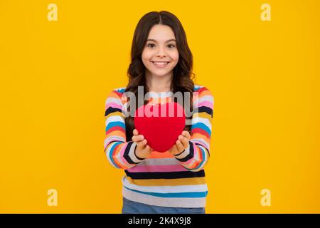 Glück Kinder und Liebe Konzept. Romantische schöne Teenager-Mädchen mit rotem Herzen, Welt Herz Tag, glücklichen Valentinstag. Fröhlicher Teenager, positiv und lächelnd Stockfoto