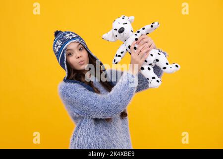 Kindheit, Spielzeug und Kinder. Niedliche Teenager-Mädchen im Winter Hut kuscheln flauschiges Spielzeug. Lustiges Gesicht. Stockfoto