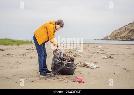Plastikmüll. Meer- und Meeresverschmutzung. Strand sauber machen. Junger Mann pflückt gebrauchte Plastikflaschen am Sandufer. Sammeln von Umweltaktivisten Stockfoto