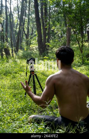 Millennial Kerl meditieren mit Trainer online über Tablet ipad-Verbindung, im Wald, online senden Ihre Klasse und Anweisungen, mexiko Stockfoto