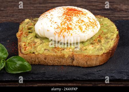 Avocado Toast mit pochiertem Ei auf einem Steinbrett zum Servieren. Speicherplatz kopieren. Stockfoto