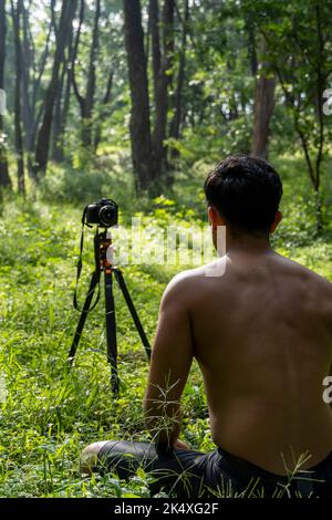 Millennial Kerl meditieren mit Trainer online über Tablet ipad-Verbindung, im Wald, online senden Ihre Klasse und Anweisungen, mexiko Stockfoto