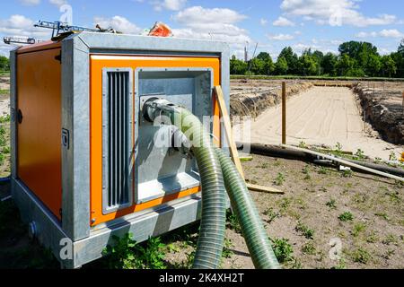 Große tragbare elektrische Wasserpumpe mit Schlauch zur Entwässerung der tiefen Grube des Gebäudefundaments, Entwässerungssystem auf der Baustelle Stockfoto