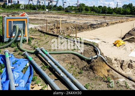 Große tragbare elektrische Wasserpumpe mit Schlauch zur Entwässerung der tiefen Grube des Gebäudefundaments, Entwässerungssystem auf der Baustelle Stockfoto