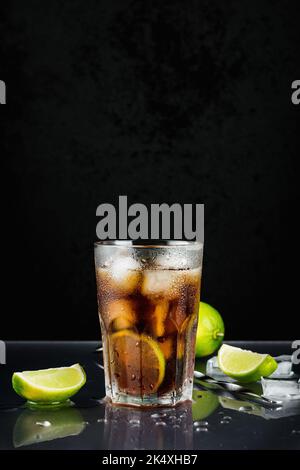 Cuba Libre Cocktail mit Limette auf schwarzem Hintergrund. Stockfoto
