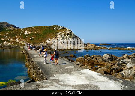 Touristen, die entlang des Damm über die Gezeitenlagune von Illa de Monteagudo nach Illa de Faro / Montefaro, Cies-Inseln, Galizien, Spanien, wandern. Stockfoto