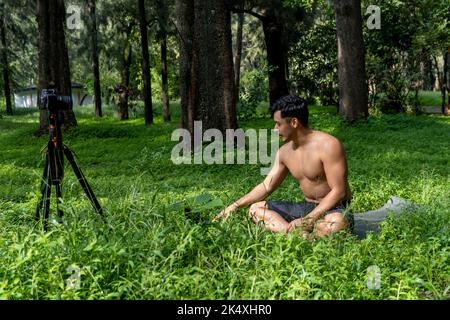 Ansicht eines Mannes, der mit einer Gruppe von Menschen zu Hause einen virtuellen Fitnesskurs durchführt, auf einer Videokonferenz. Fitnesstrainer, der Online-Yoga-Kurse besucht Stockfoto