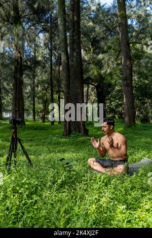 Ansicht eines Mannes, der mit einer Gruppe von Menschen zu Hause einen virtuellen Fitnesskurs durchführt, auf einer Videokonferenz. Fitnesstrainer, der Online-Yoga-Kurse besucht Stockfoto