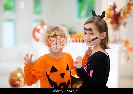 Kind im Halloween Kostüm. Kinder können sich verwöhnen lassen. Kleiner Junge und Mädchen in Hexenkleid mit Kürbis Laterne. Bruder und Schwester mit Süßigkeiteneimer. Stockfoto