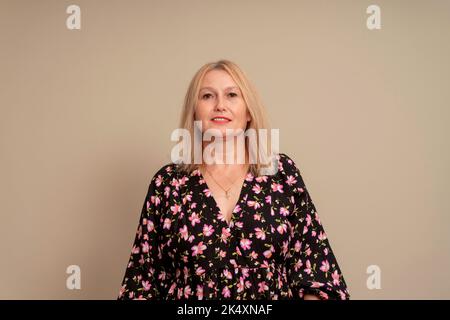 Fröhlich lächelnde Frau mit blonden Haaren, lässig angezogen, mit Zufriedenheit in die Kamera schauend, glücklich sein. Studioaufnahme der schönen hübschen Frau Stockfoto