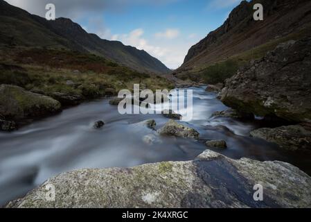 Bach, der mit weichem, nebligen Wasser den Berg hinunter läuft. Langandauerndes fließendes Wasser Stockfoto