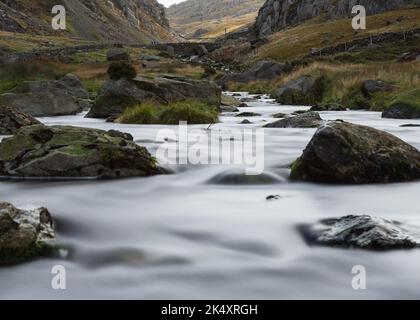 Bach, der mit weichem, nebligen Wasser den Berg hinunter läuft. Langandauerndes fließendes Wasser Stockfoto