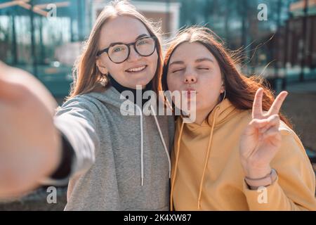 Zwei junge lächelnde Hipster-Frauen, die Selfie-Selbstporträts auf dem Smartphone machen und positive Emotionen zeigen Stockfoto