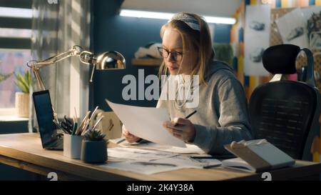 Die junge Künstlerin zeichnet Bleistiftskizzen auf ein Blatt Papier. Der Illustrator erstellt ein Storyboard mit Blick auf den Laptop-Bildschirm. Storytelling-Konzept. Videobearbeitung. Stockfoto