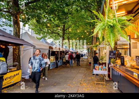 Shopper shoppen und spazieren durch den Open-Air-Lebensmittelmarkt entlang der Baumgrenzen der Parliament Street in der Stadt York, Yorkshire. Stockfoto