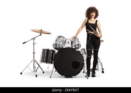 Drummerin, die neben einem Schlagzeug steht und auf weißem Hintergrund isolierte Drumsticks hält Stockfoto