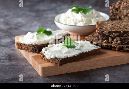 Roggenbrotscheiben mit Quark auf grauem Hintergrund Stockfoto
