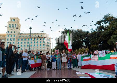 Barcelona, Spanien. 04. Oktober 2022. Vögel fliegen herüber, während Demonstranten Plakate und iranische Flaggen während der Demonstration halten. Ähnliche Demonstrationen wurden in Städten auf der ganzen Welt abgehalten, um Gerechtigkeit für die Tötung von Mahsa Amini zu fordern, einer jungen Frau, die von der iranischen Moralpolizei in Teheran inhaftiert wurde, weil sie den Hijab nicht ordnungsgemäß in der Öffentlichkeit trug. Kredit: SOPA Images Limited/Alamy Live Nachrichten Stockfoto