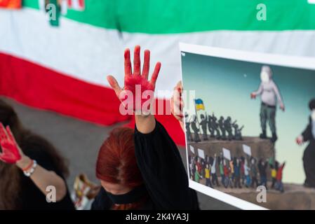 Barcelona, Spanien. 04. Oktober 2022. Eine Protesterin hebt während der Demonstration eine rot gemalte Hand gegen die iranische Flagge. Ähnliche Demonstrationen wurden in Städten auf der ganzen Welt abgehalten, um Gerechtigkeit für die Tötung von Mahsa Amini zu fordern, einer jungen Frau, die von der iranischen Moralpolizei in Teheran inhaftiert wurde, weil sie den Hijab nicht ordnungsgemäß in der Öffentlichkeit trug. Kredit: SOPA Images Limited/Alamy Live Nachrichten Stockfoto