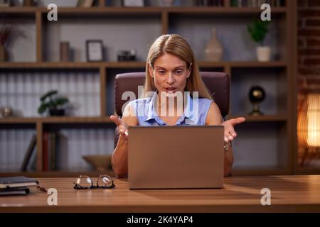 Frau kommuniziert über Video-Link, während sie aus der Ferne arbeitet. Selbstbewusste Freiberuflerin spricht und gestikiert, hält eine Online-Konferenz ab und schaut Stockfoto