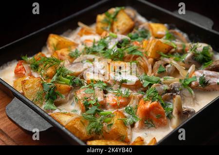 Bratkartoffeln mit Lachs und Pilzen mit Sauce Stockfoto