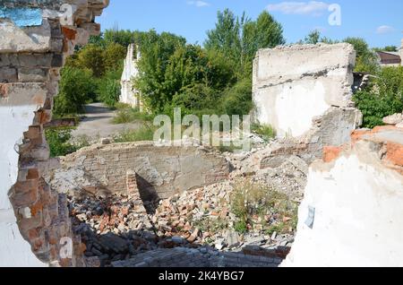 Eingestürzter mehrstöckiger Industriebau tagsüber. Katastrophenort voller Trümmer, zerbrochener Ziegelsteine und beschädigtem Haus ohne Wohngebäude. Konzept des Krieges AC Stockfoto