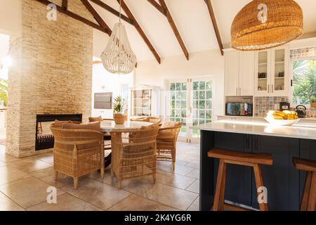 Gesamtansicht der modernen Küche mit Tisch, Stühlen, Arbeitsplatte und Kamin. Haus Interieur und Design-Konzept. Stockfoto