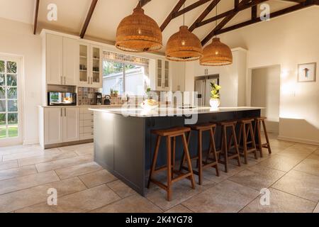 Gesamtansicht der modernen Küche mit Arbeitsplatte, Stühlen und Küchenausstattung. Haus Interieur und Design-Konzept. Stockfoto