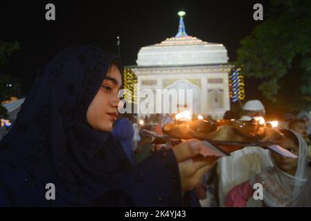 Lahore, Punjab, Pakistan. 4. Oktober 2022. Pakistanische muslimische Anhänger zünden Kerzen an Erdöllampen an und Devotes (Malang) tanzen am Schrein des berühmten Sufi-Heiligen Hazrat mir Mohammed Muayyinul aus dem 15. Jahrhundert während der 399. URS-Geburtstagfeier in Lahore. Tausende von Menschen im ganzen Land besuchen den Schrein, um ihm während eines dreitägigen Festivals Tribut zu zollen. Der heilige war unter den muslimischen und den Sikh-Religionen gleichermaßen beliebt, als Mian mir im Dezember 1588 nach Amritsar (Indien) ging, um den Grundstein für Sikhs heiligste Stätte, den Goldenen Tempel, der allgemein als Sri bekannt ist, zu legen Stockfoto
