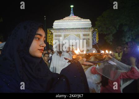 Lahore, Punjab, Pakistan. 4. Oktober 2022. Pakistanische muslimische Anhänger zünden Kerzen an Erdöllampen an und Devotes (Malang) tanzen am Schrein des berühmten Sufi-Heiligen Hazrat mir Mohammed Muayyinul aus dem 15. Jahrhundert während der 399. URS-Geburtstagfeier in Lahore. Tausende von Menschen im ganzen Land besuchen den Schrein, um ihm während eines dreitägigen Festivals Tribut zu zollen. Der heilige war unter den muslimischen und den Sikh-Religionen gleichermaßen beliebt, als Mian mir im Dezember 1588 nach Amritsar (Indien) ging, um den Grundstein für Sikhs heiligste Stätte, den Goldenen Tempel, der allgemein als Sri bekannt ist, zu legen Stockfoto