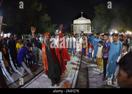 Lahore, Punjab, Pakistan. 4. Oktober 2022. Pakistanische muslimische Anhänger zünden Kerzen an Erdöllampen an und Devotes (Malang) tanzen am Schrein des berühmten Sufi-Heiligen Hazrat mir Mohammed Muayyinul aus dem 15. Jahrhundert während der 399. URS-Geburtstagfeier in Lahore. Tausende von Menschen im ganzen Land besuchen den Schrein, um ihm während eines dreitägigen Festivals Tribut zu zollen. Der heilige war unter den muslimischen und den Sikh-Religionen gleichermaßen beliebt, als Mian mir im Dezember 1588 nach Amritsar (Indien) ging, um den Grundstein für Sikhs heiligste Stätte, den Goldenen Tempel, der allgemein als Sri bekannt ist, zu legen Stockfoto