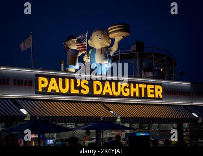 New York, NY - USA - 3. September 2022 Nachtansicht des Neonzeichens von Pauls Tochter mit ihren ikonischen Dachstatuen einer Familie, die hamb schwingt Stockfoto